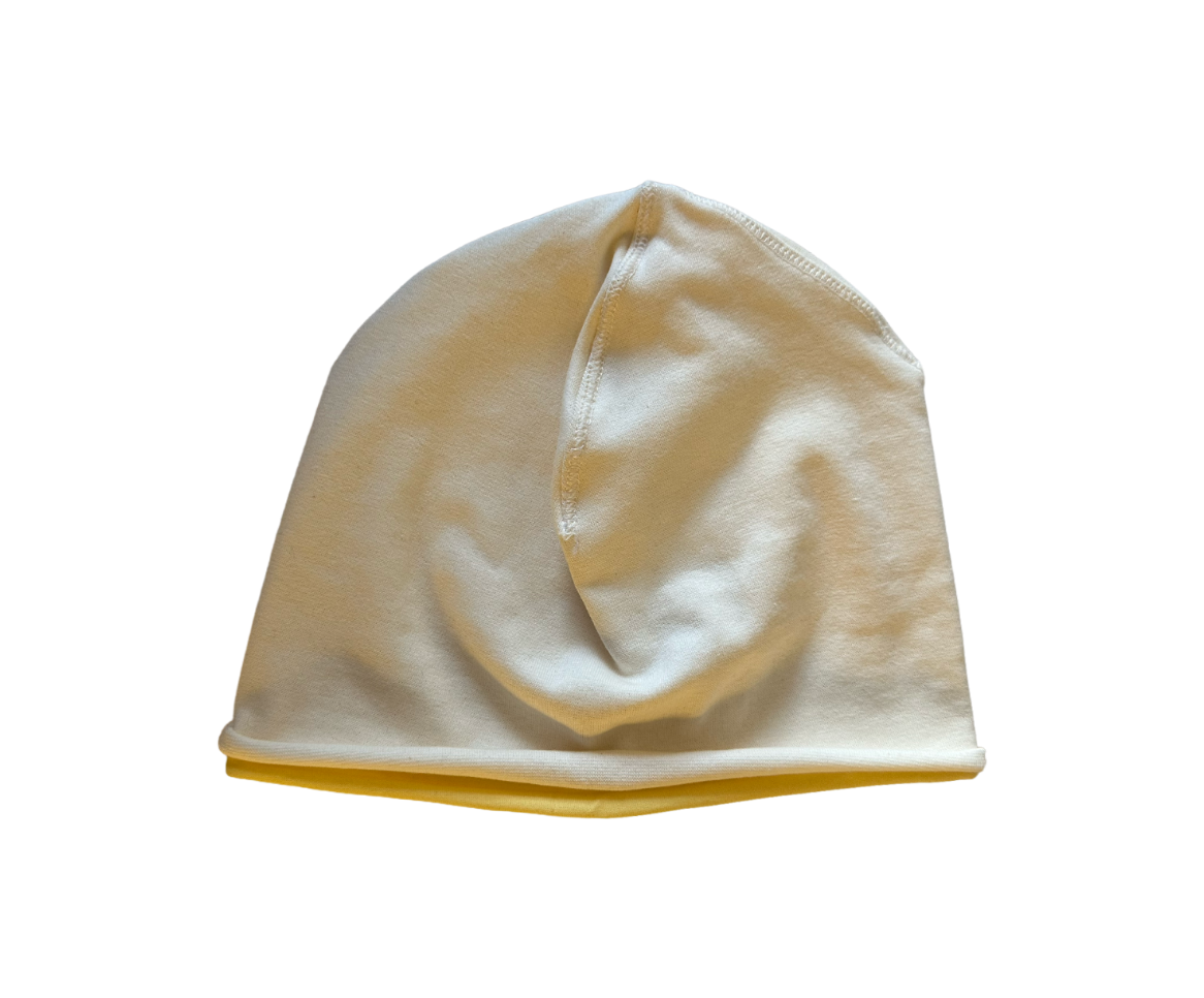 A soft knit beanie hat in a warm off-white or cream color, shown against a plain white background.